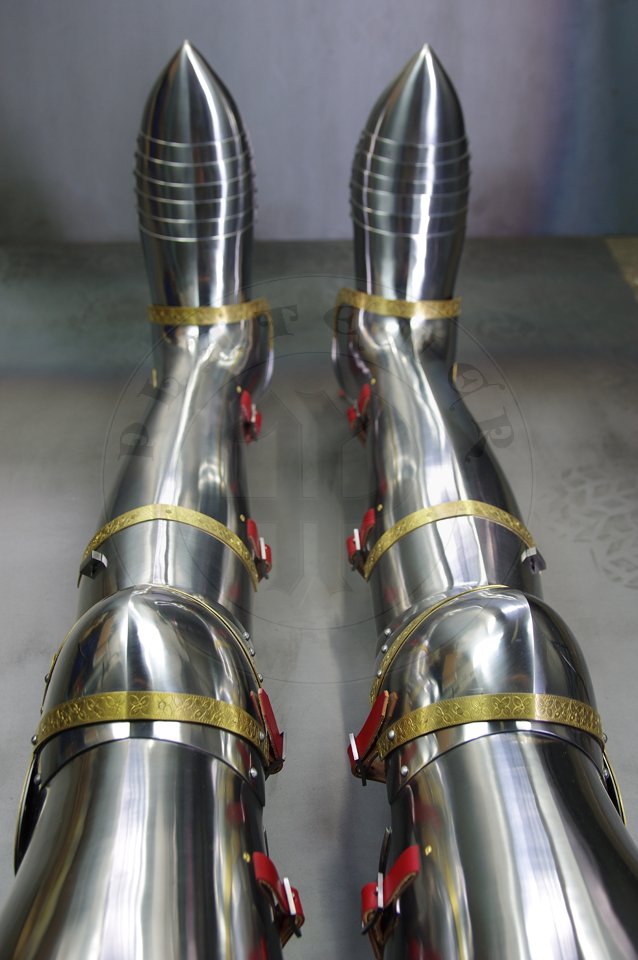 English style leg harness with fully closed cuisses, full greaves with characteristic line around outside ankles. Demi-greaves connected with greaves on rotary pin. Made of medium carbon steel of various thickness from 1 mm up to 1,5 mm. Heat hardened and tempered up to 42 HRC. Brass bands decoration motive based on example visible on Henry V tournament helm. Hand made steel buckles in set./Osony ng w stylu angielskim z w peni zamknitymi nabiodrkami, nagolennicami z charakterystyczn lini wok zewntrznej kostki. Demi-greave poczony z nagolennicami poprzez obrotowy pin. Wykonane ze stali redniowglowej rnej gruboci od 1 mm do 1,5 mm. Hartowane i odpuszczane do 42 HRC. Mosine listwy dekoracyjne z motywem wzorowanym na hemie turniejowym Henryka V. W zestawie rcznie robione sprzczki stalowe.